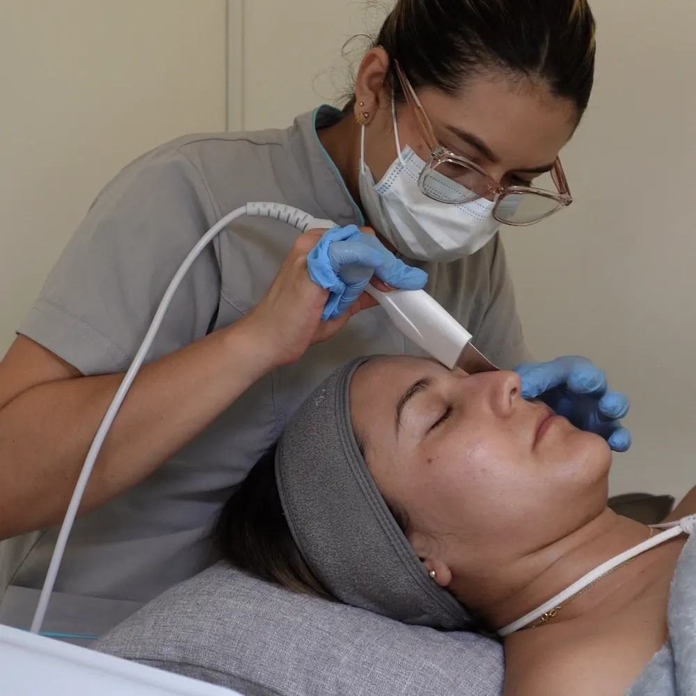 Nuestra esteticista haciendo una limpieza facial con espátula ultrasónica a una paciente en el consultorio